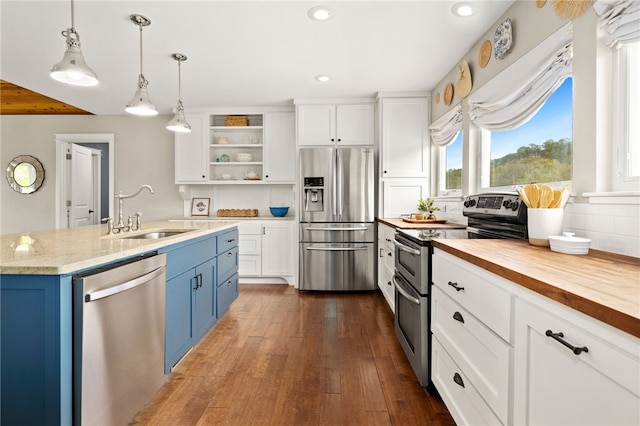 kitchen with wood counters, stainless steel appliances, blue cabinetry, and a sink