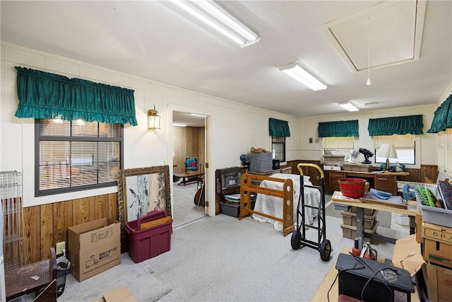interior space featuring attic access, wooden walls, and carpet flooring