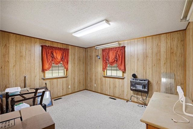 carpeted office with heating unit, wood walls, and a textured ceiling