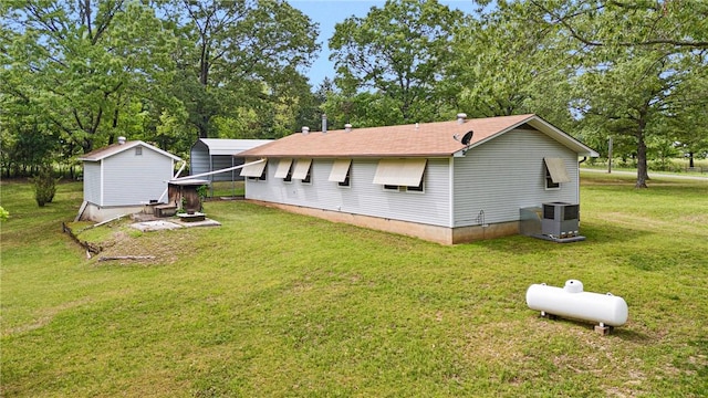 back of property featuring roof with shingles, cooling unit, and a lawn