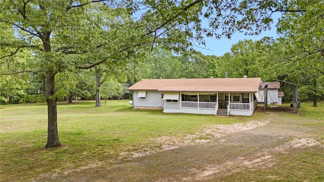 view of front of house with a front lawn, driveway, a detached carport, and covered porch