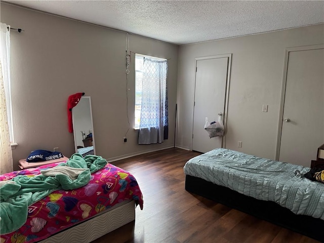 bedroom featuring a textured ceiling, wood finished floors, and baseboards