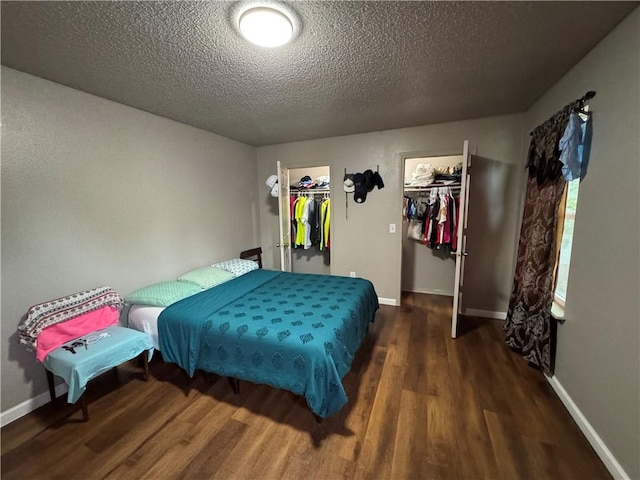 bedroom with a closet, baseboards, a textured ceiling, wood finished floors, and a spacious closet