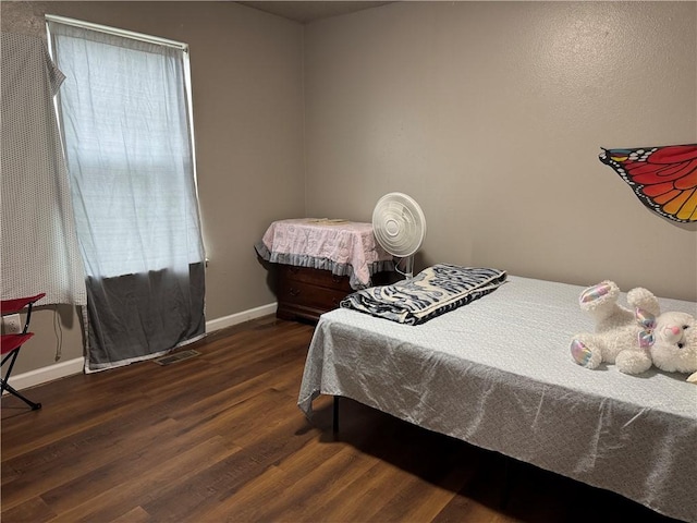 bedroom with multiple windows, wood finished floors, visible vents, and baseboards