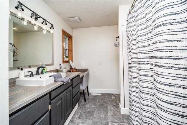 full bath featuring stone finish flooring, a shower with shower curtain, vanity, baseboards, and a textured ceiling