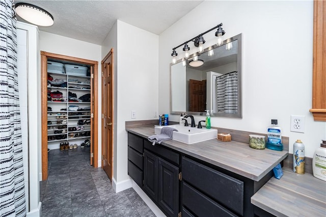 full bath featuring baseboards, vanity, and a spacious closet