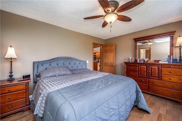 bedroom with a ceiling fan, wood finished floors, and a textured ceiling