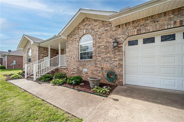 doorway to property with a garage, brick siding, and driveway