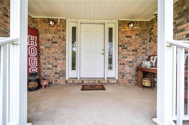 doorway to property with brick siding and a porch