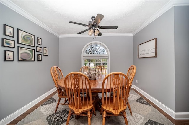 dining room featuring ornamental molding, ceiling fan, baseboards, and dark wood finished floors