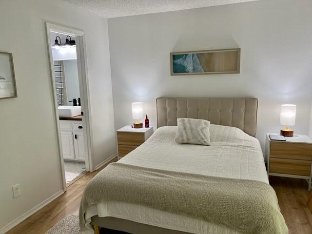 bedroom with baseboards, wood finished floors, and ensuite bath