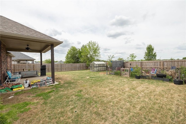 view of yard with an outdoor structure, a patio, a garden, and a fenced backyard