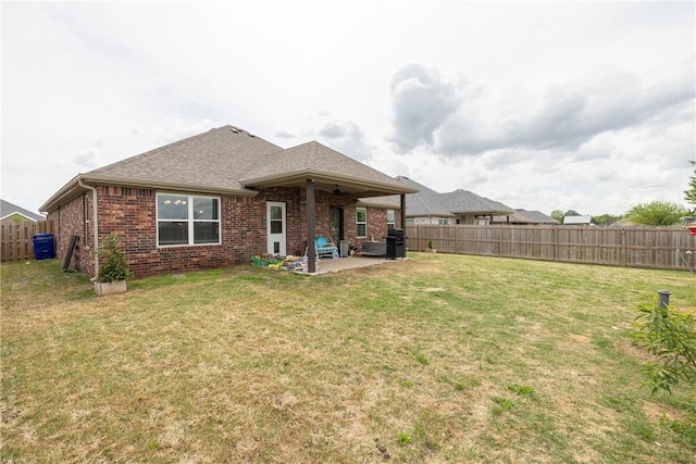 rear view of house with a patio area, a yard, a fenced backyard, a ceiling fan, and brick siding