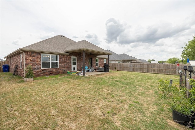 rear view of property with a patio, brick siding, a fenced backyard, a lawn, and roof with shingles