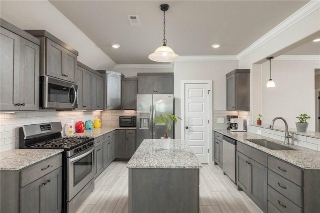 kitchen with light stone countertops, a sink, a center island, backsplash, and appliances with stainless steel finishes