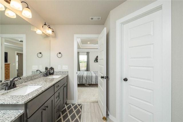 ensuite bathroom featuring visible vents, connected bathroom, double vanity, and a sink