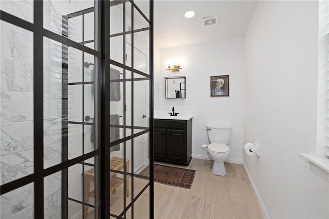 bathroom with visible vents, wood finished floors, vanity, baseboards, and toilet
