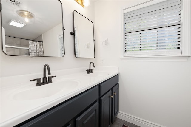 bathroom featuring double vanity, a sink, baseboards, and visible vents