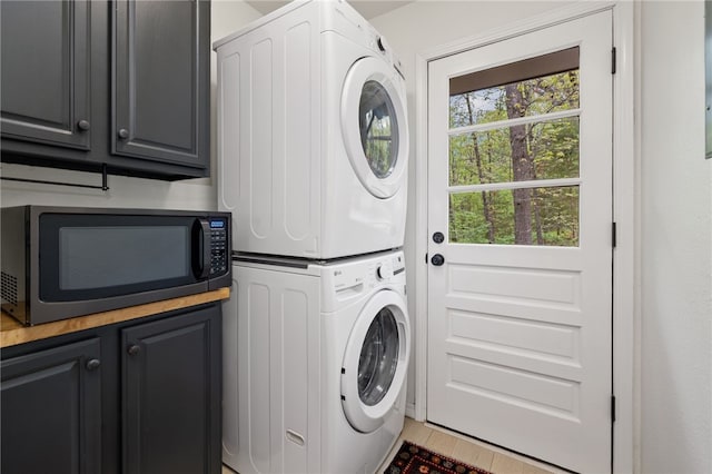 clothes washing area with laundry area, tile patterned flooring, and stacked washer and clothes dryer