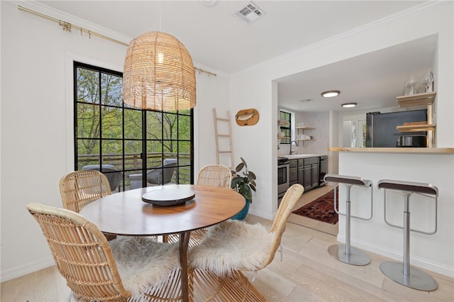 dining space featuring crown molding, baseboards, light wood-type flooring, and visible vents