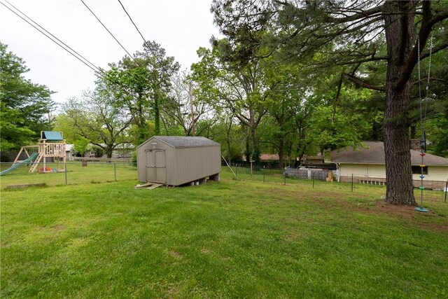 view of yard with an outdoor structure, a playground, fence, and a shed