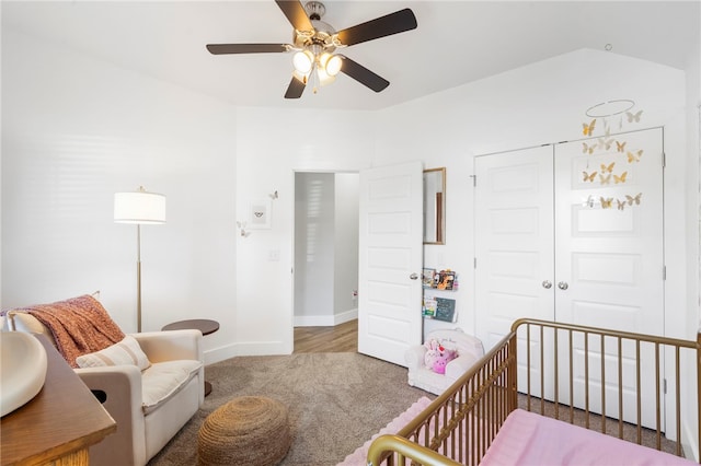 carpeted bedroom featuring a nursery area, baseboards, ceiling fan, and a closet