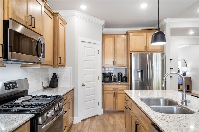kitchen featuring decorative light fixtures, tasteful backsplash, light wood-type flooring, a sink, and stainless steel appliances