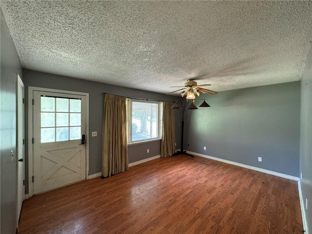 unfurnished room featuring a textured ceiling, ceiling fan, baseboards, and wood finished floors