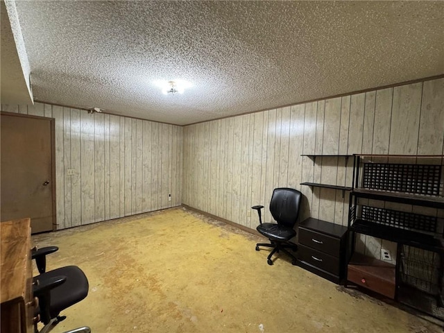 office with a textured ceiling, concrete flooring, and wooden walls