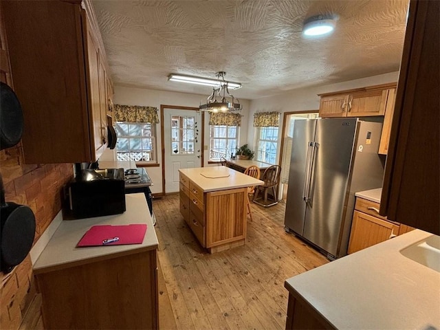 2525 Dustin Ln, Omaha, AR 72662 - kitchen featuring brown cabinets, high end fridge, light countertops, a center island, and light wood-type flooring
