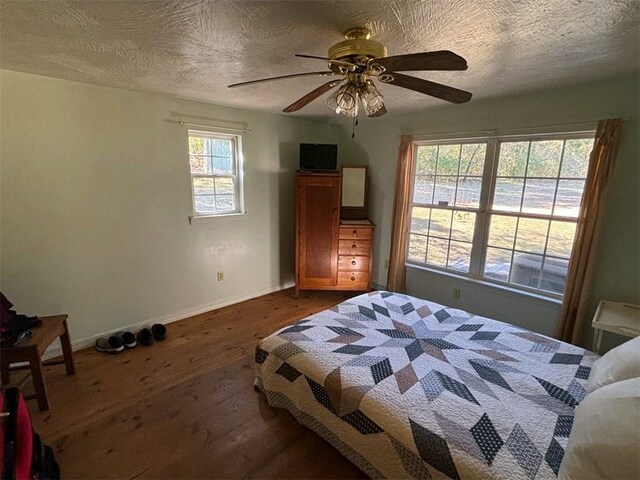 2525 Dustin Ln, Omaha, AR 72662 - bedroom with a textured ceiling, baseboards, dark wood-style floors, and a ceiling fan