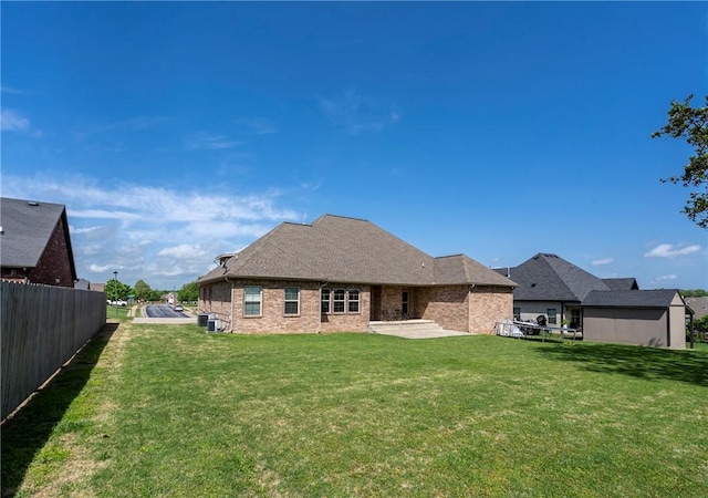 back of property featuring a lawn, a patio area, fence, and brick siding