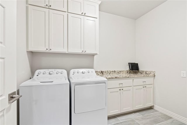 laundry area with separate washer and dryer, baseboards, and cabinet space