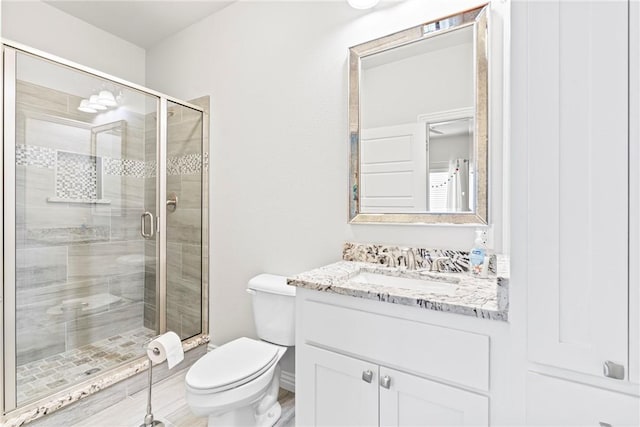 full bathroom featuring vanity, a shower stall, and toilet