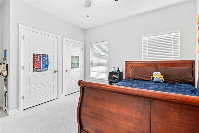 bedroom with a ceiling fan, baseboards, light colored carpet, and visible vents
