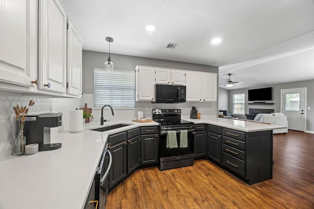 kitchen with visible vents, a sink, black microwave, white cabinetry, and electric stove