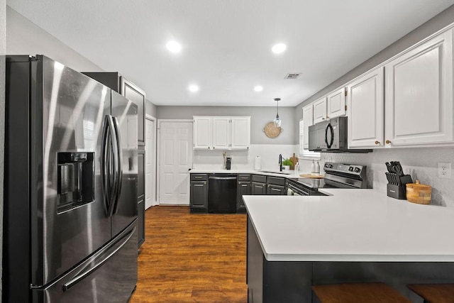 kitchen with dark wood-style flooring, visible vents, a sink, black appliances, and a peninsula