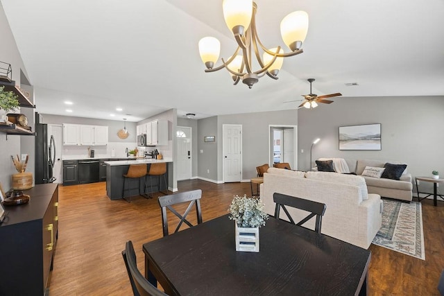 dining room with dark wood-style flooring, lofted ceiling, baseboards, recessed lighting, and ceiling fan with notable chandelier