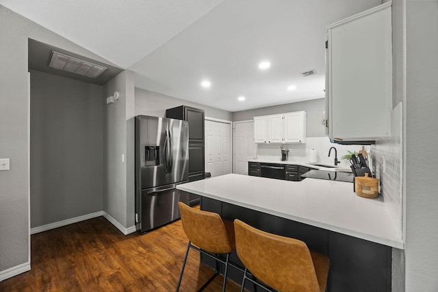 kitchen with visible vents, a peninsula, dishwashing machine, stainless steel fridge, and a sink