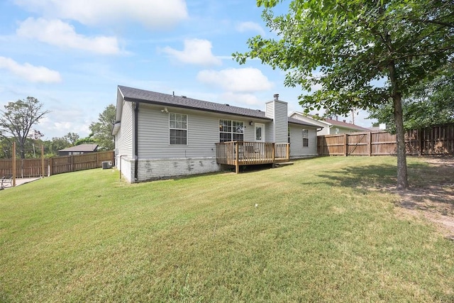 rear view of house with a fenced backyard, a chimney, a yard, and a deck