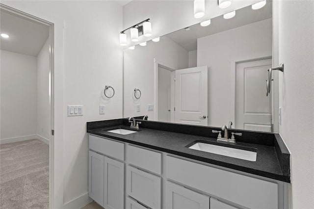 bathroom with double vanity, a sink, and baseboards