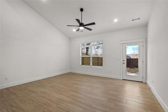 spare room featuring a ceiling fan, visible vents, baseboards, lofted ceiling, and light wood-style floors