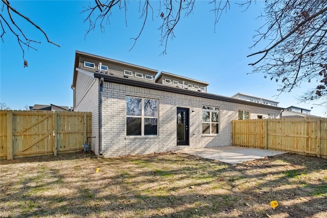 rear view of house featuring a fenced backyard, a gate, a patio, and brick siding
