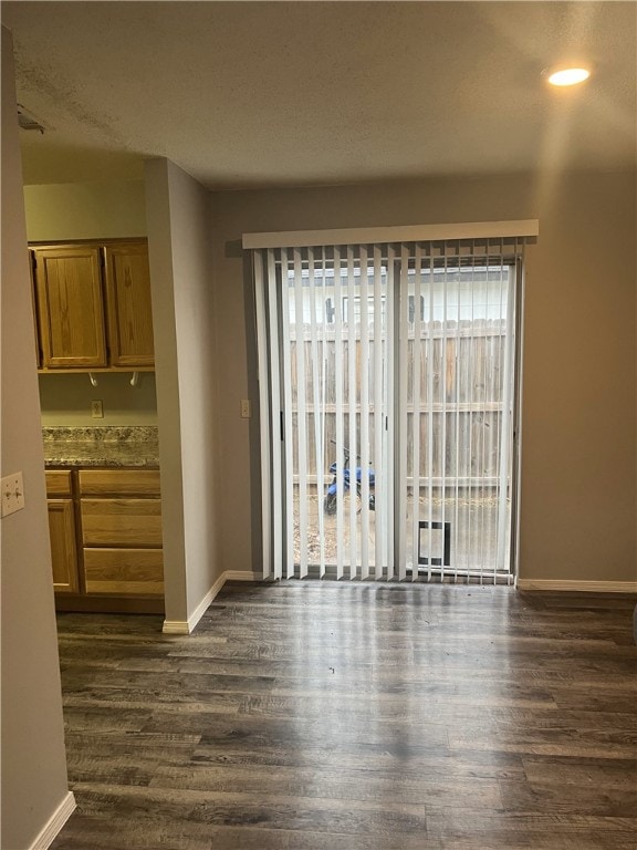 unfurnished dining area featuring baseboards, dark wood finished floors, and a healthy amount of sunlight