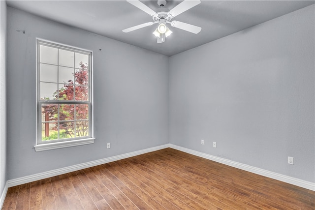 spare room featuring baseboards, wood-type flooring, and a ceiling fan