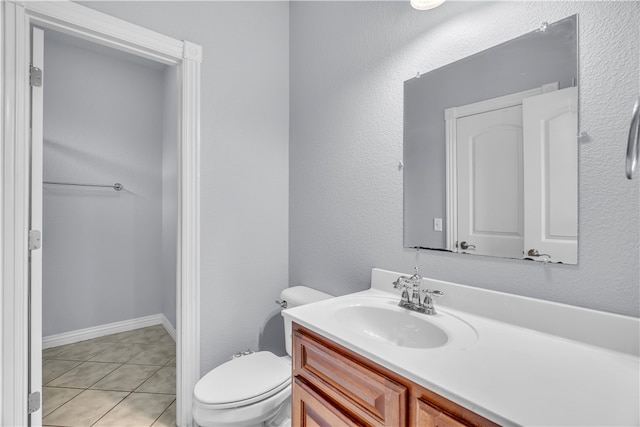 half bathroom with vanity, tile patterned flooring, and toilet