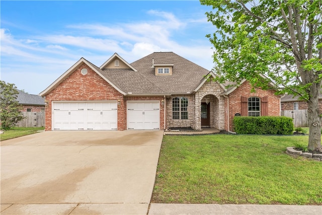 traditional home featuring a garage, fence, a front yard, roof with shingles, and driveway