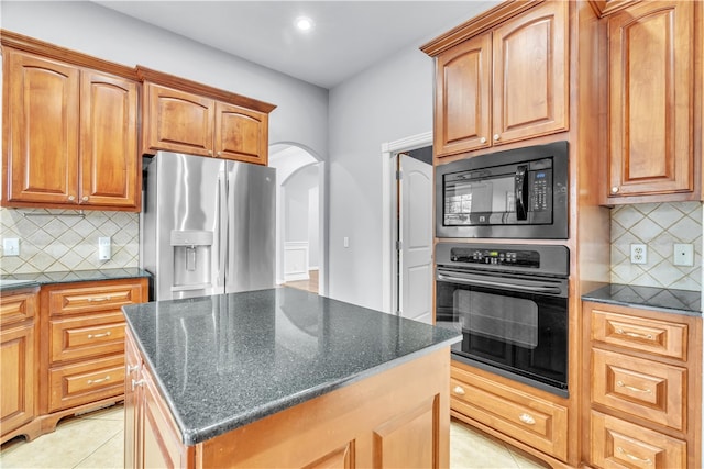 kitchen with black microwave, arched walkways, wall oven, backsplash, and stainless steel refrigerator with ice dispenser