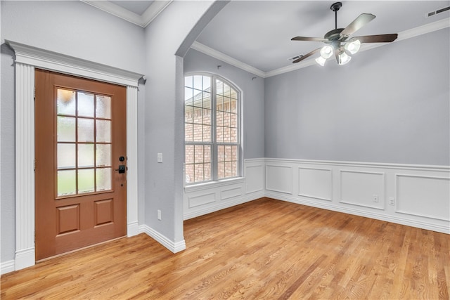 foyer featuring ceiling fan, visible vents, crown molding, arched walkways, and light wood-style flooring