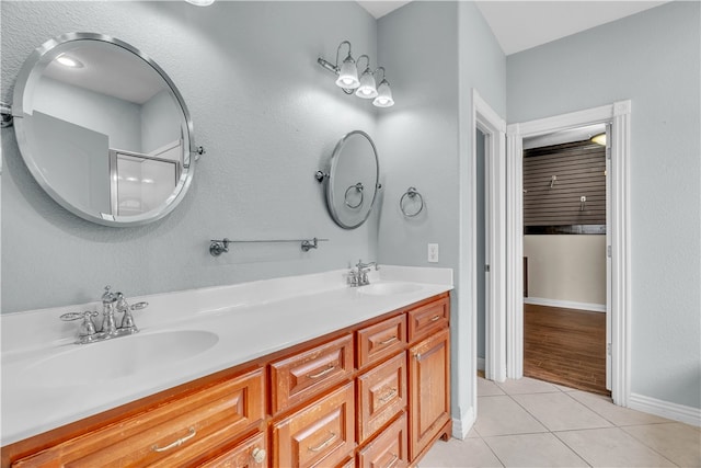 full bath with baseboards, double vanity, tile patterned floors, and a sink